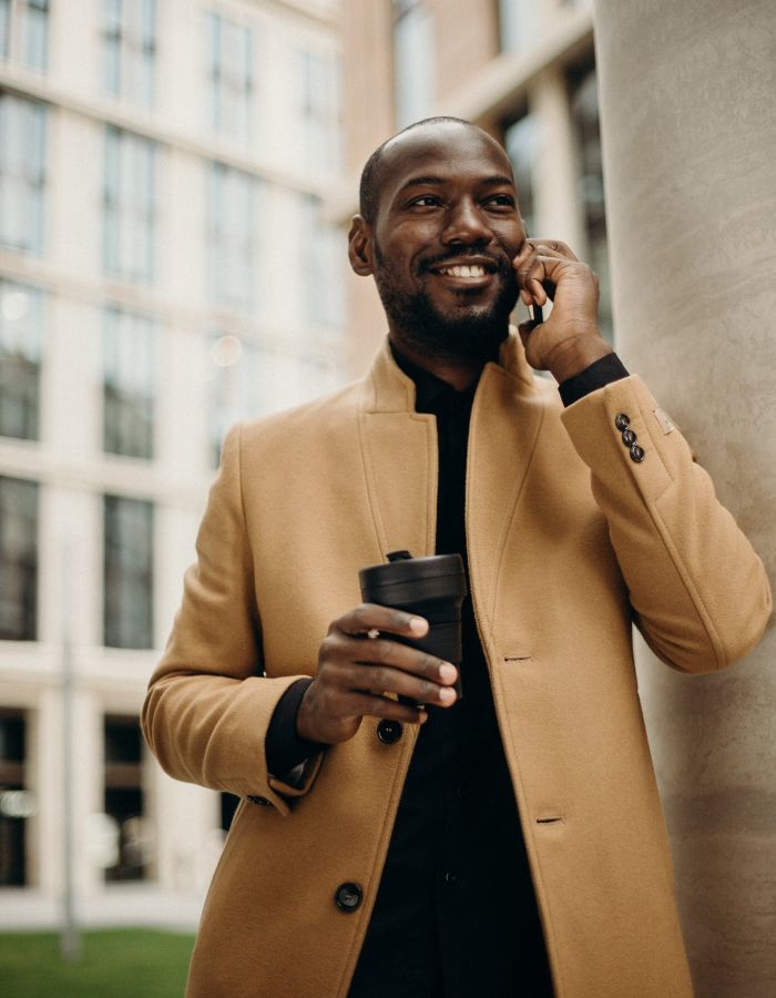 Business man on the phone smiling holding a coffee cup